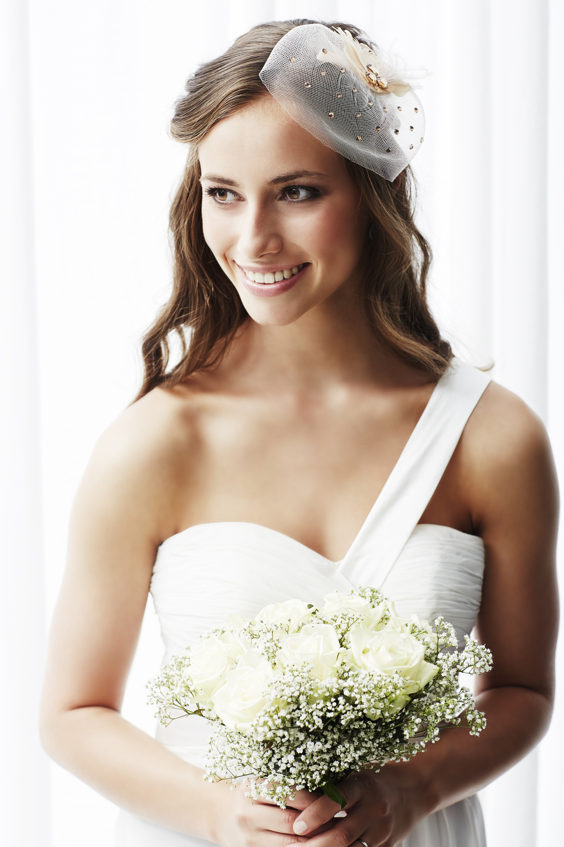 Young bride in wedding dress holding bouquet, studio shot .